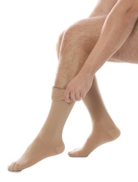 Man putting on compression stocking against white background, closeup