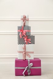 Photo of Many gift boxes with colorful bows near white wall
