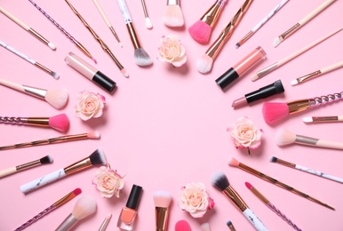 Photo of Frame of makeup products and roses on pink background, flat lay. Space for text