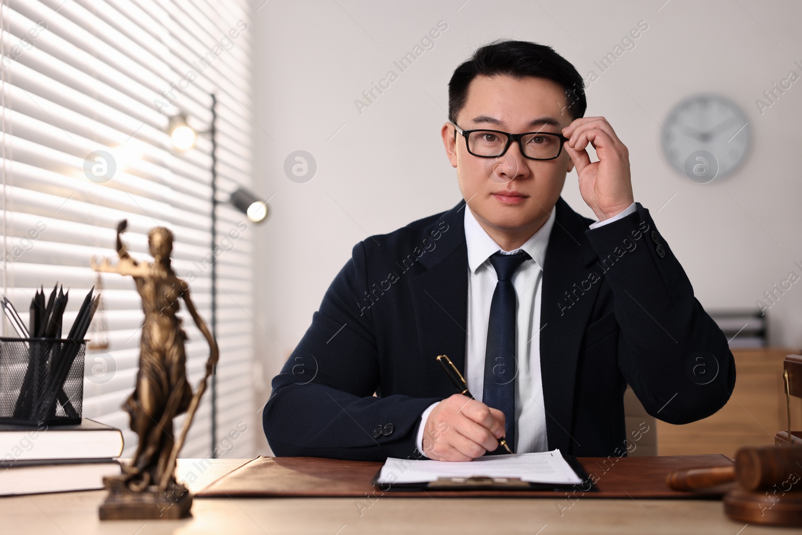 Photo of Notary writing notes at wooden table in office