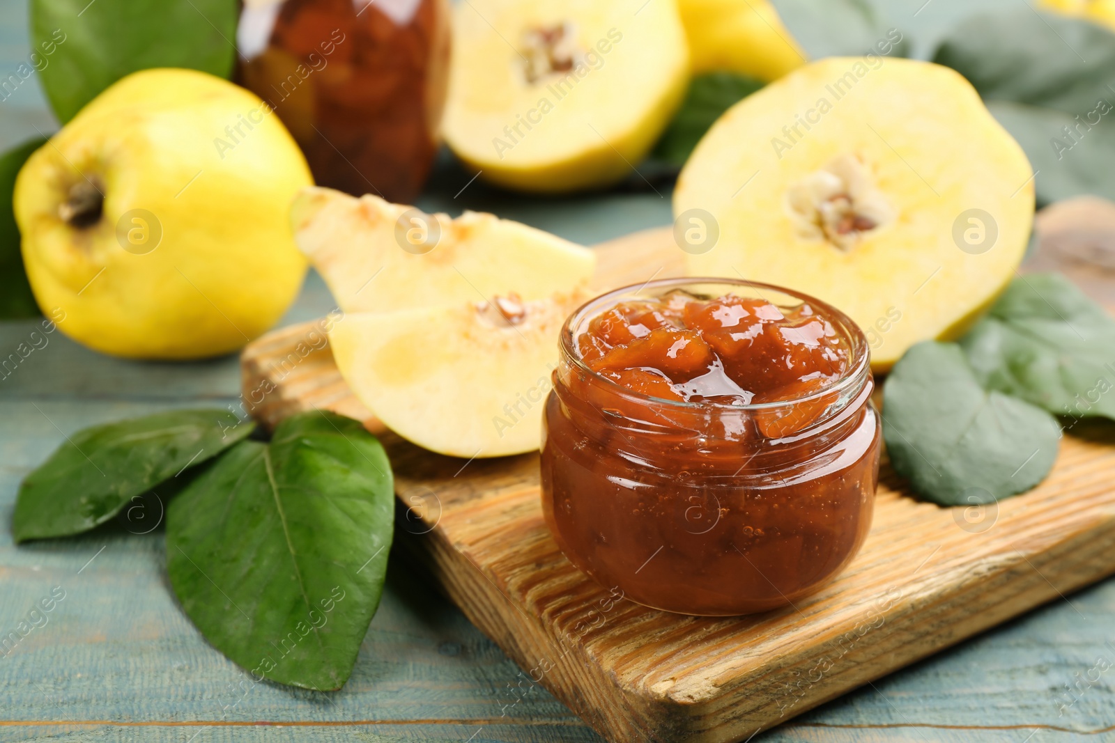 Photo of Delicious quince jam on light blue wooden table, closeup