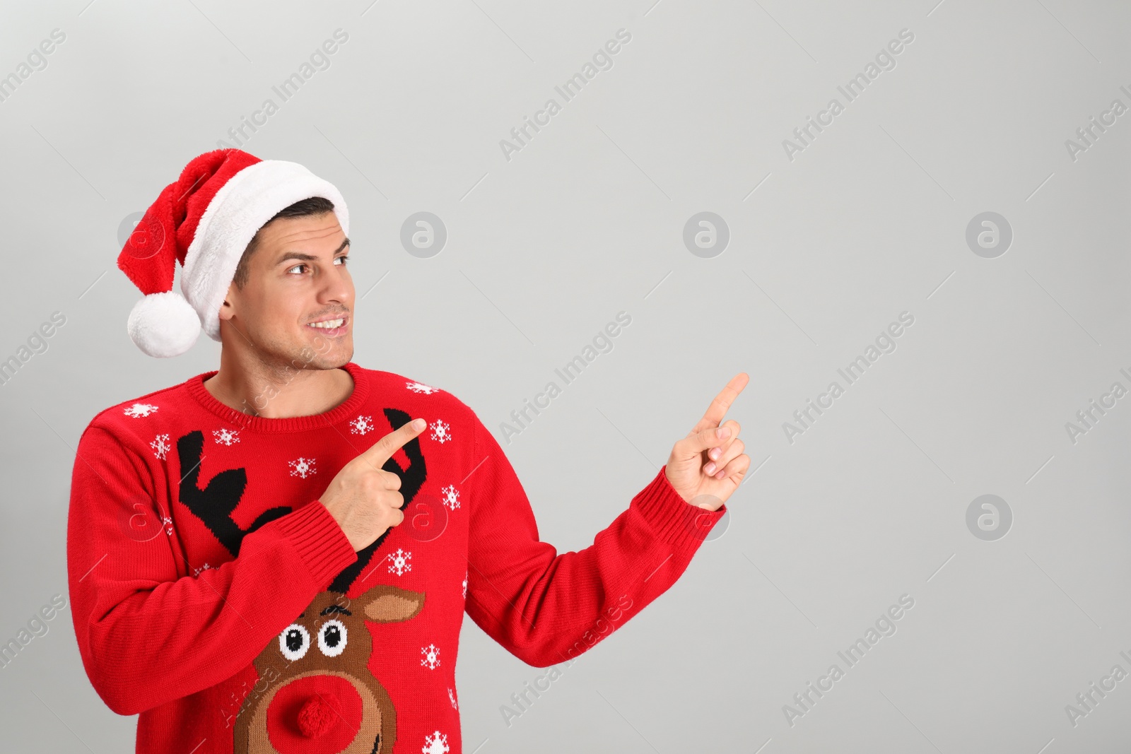 Photo of Handsome man wearing Santa hat on grey background, space for text