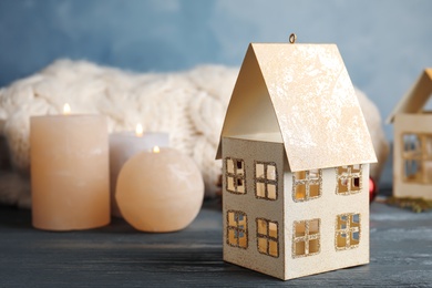 Composition with candle in house shaped holder on grey wooden table. Christmas decoration