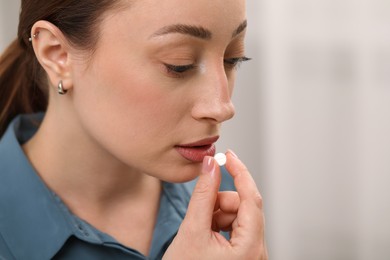 Photo of Depressed woman taking antidepressant pill on light background, closeup