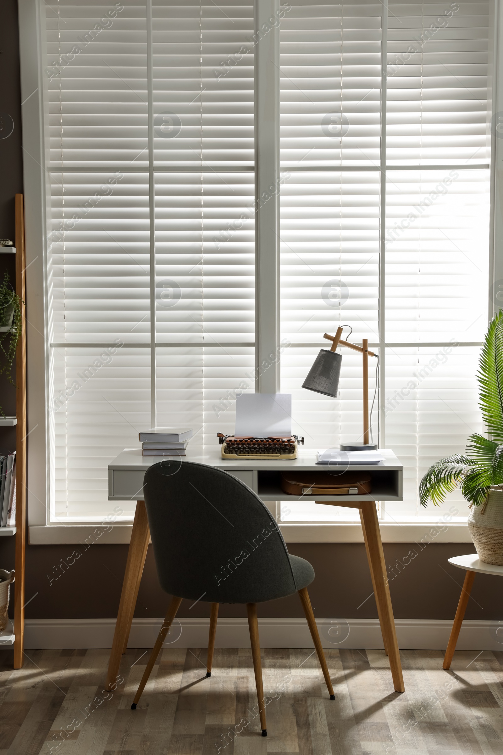 Photo of Comfortable writer's workplace interior with typewriter on desk in front of window