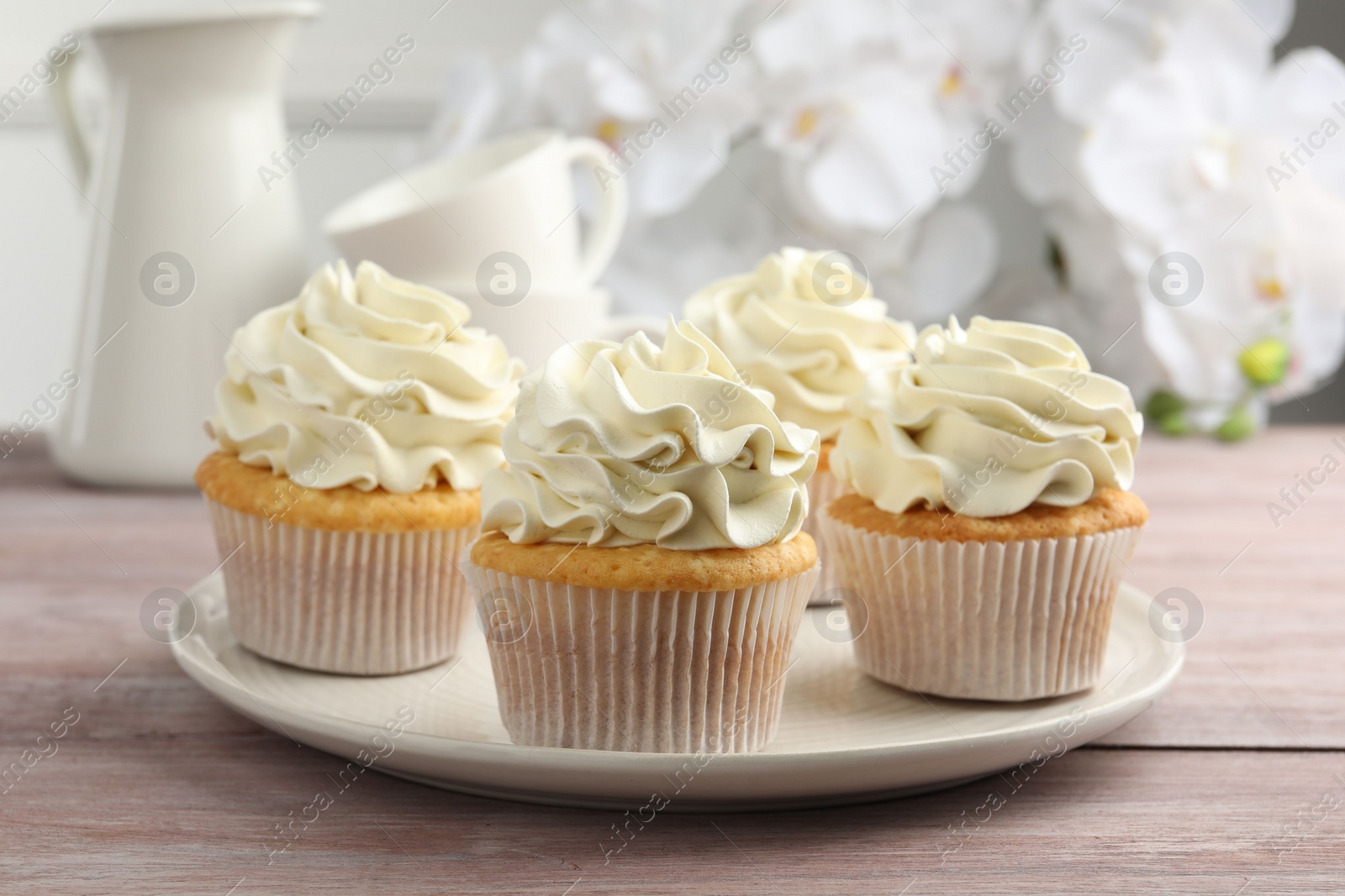 Photo of Tasty cupcakes with vanilla cream on pink wooden table, closeup