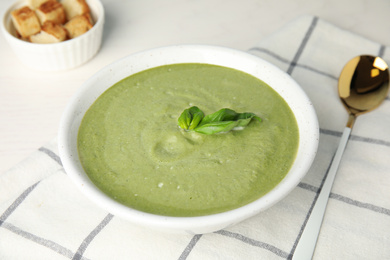 Photo of Delicious broccoli cream soup served on white table