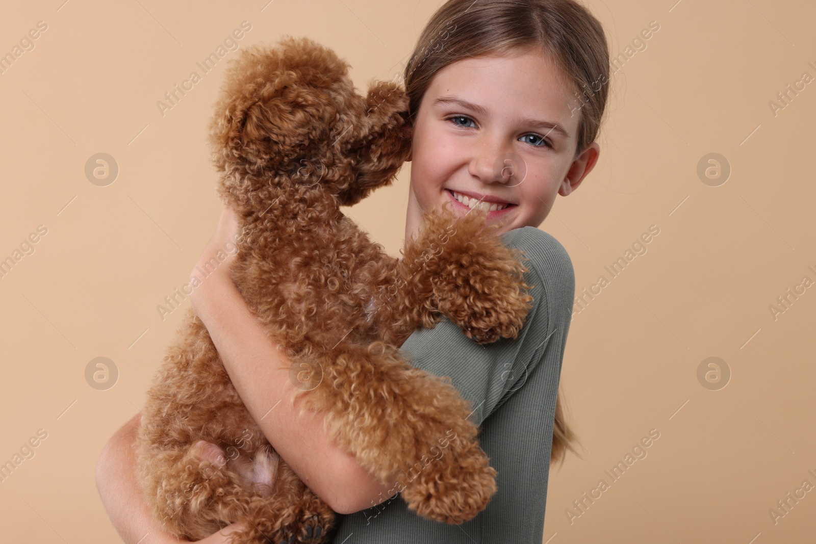 Photo of Little child with cute puppy on beige background. Lovely pet