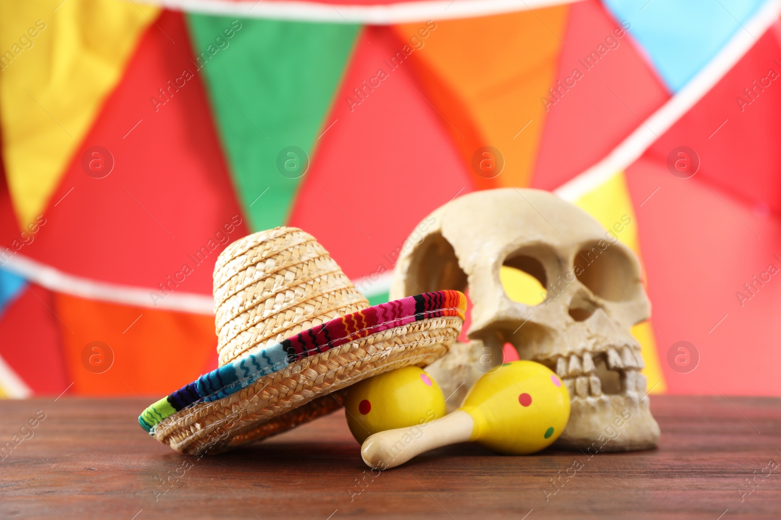 Photo of Mexican sombrero hat, human scull and maracas on wooden table