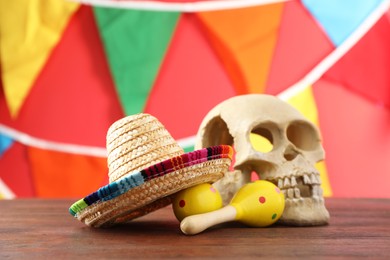 Photo of Mexican sombrero hat, human scull and maracas on wooden table