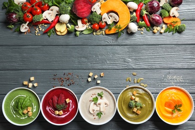 Various cream soups, ingredients and space for text on wooden background, flat lay. Healthy food