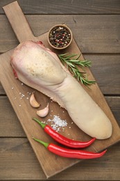 Raw beef tongue, peppercorns, garlic, salt, rosemary and chili peppers on wooden table, top view