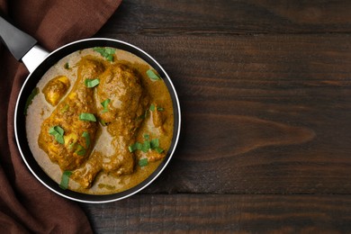 Photo of Delicious chicken with curry sauce on wooden table, top view. Space for text