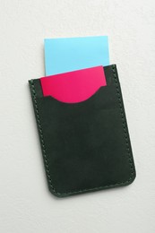 Leather business card holder with colorful cards on white table, top view
