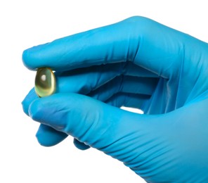 Scientist in protective gloves holding pill on white background, closeup