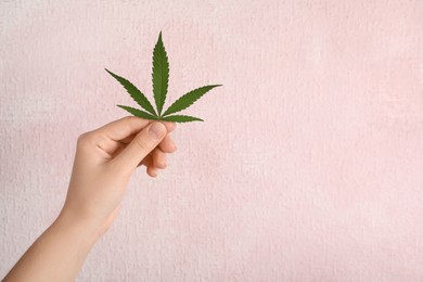 Photo of Woman holding hemp leaf on light background, closeup. Space for text