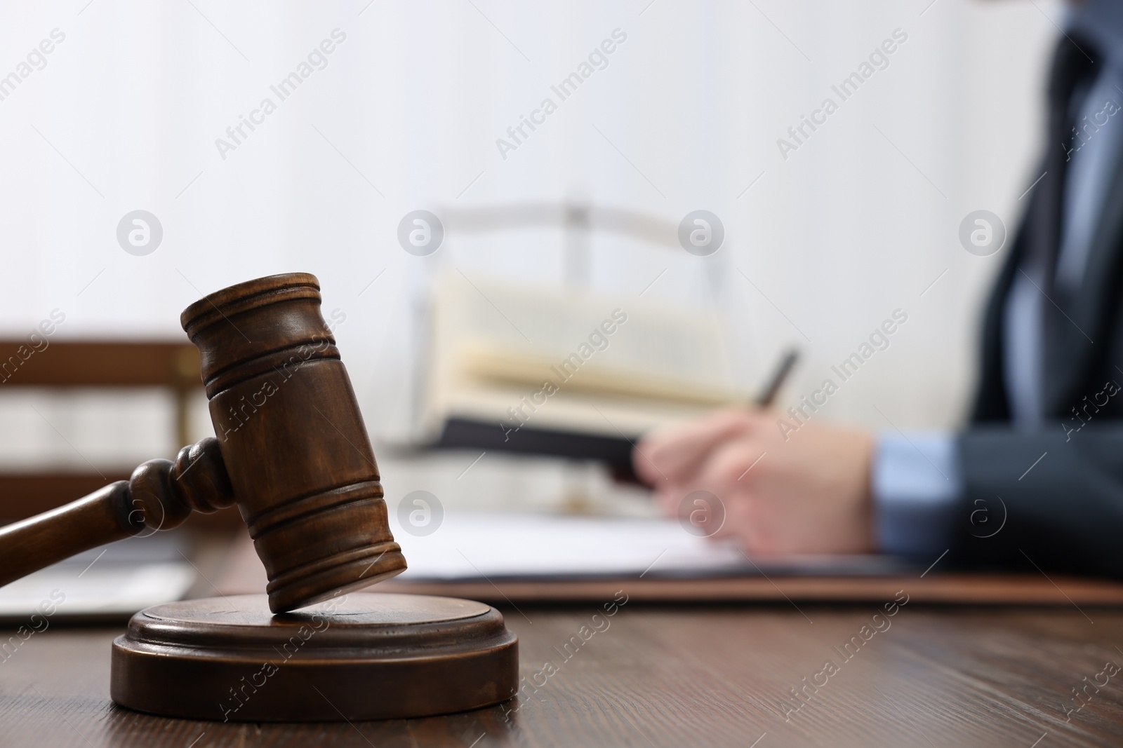 Photo of Lawyer working with documents at wooden table, focus on gavel