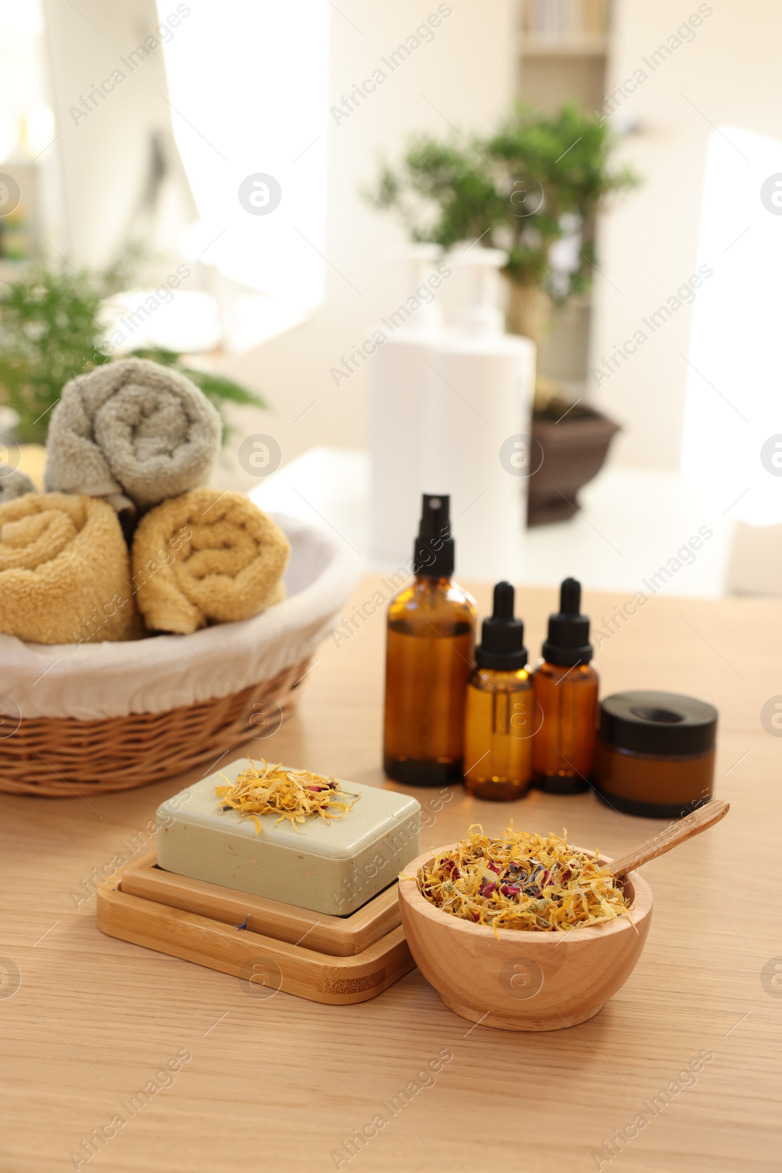 Photo of Soap bar, dry flowers, bottles of essential oils, jar with cream and towels on wooden table indoors. Spa time