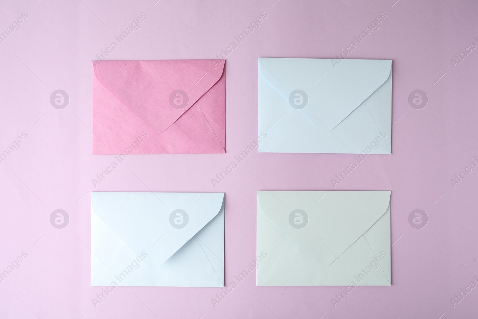 Photo of Colorful paper envelopes on pink background, flat lay