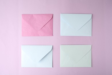 Photo of Colorful paper envelopes on pink background, flat lay