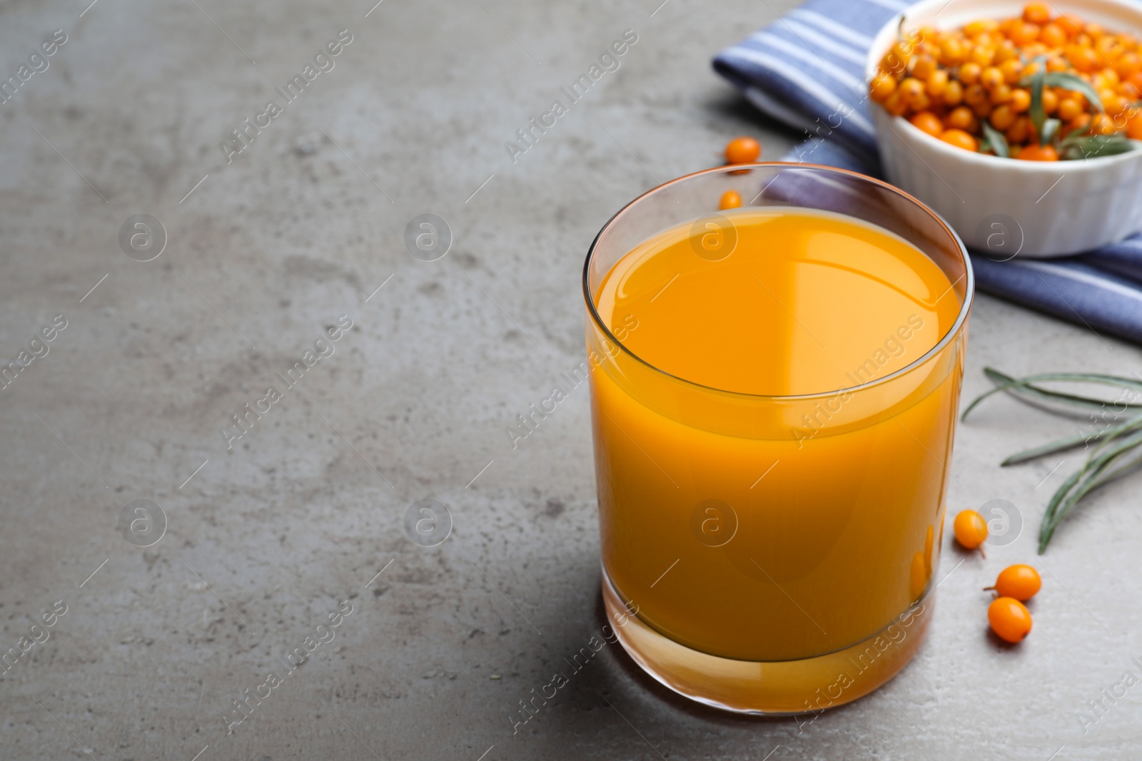 Photo of Delicious sea buckthorn juice on grey table. Space for text