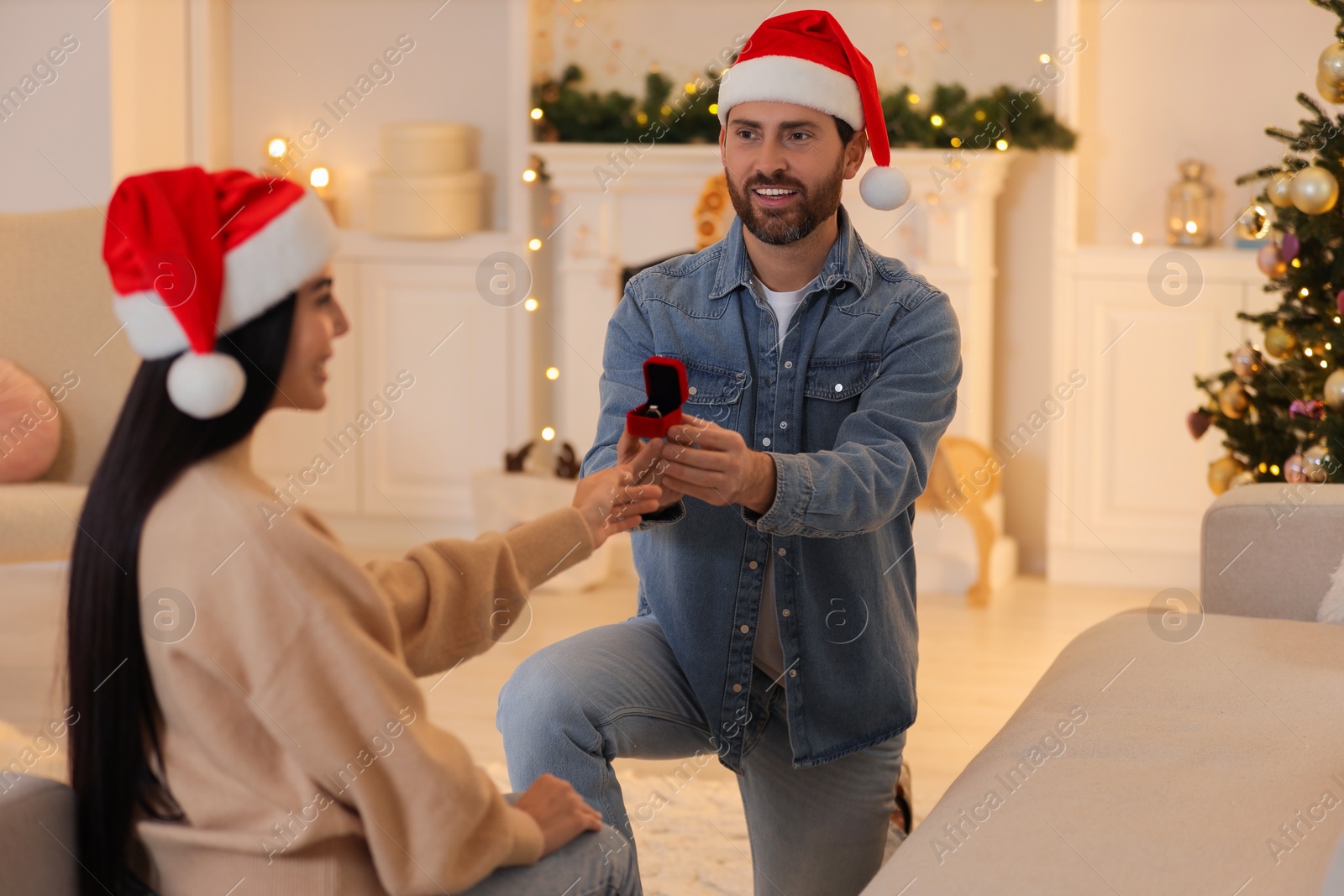 Photo of Man with engagement ring making proposal to his girlfriend at home on Christmas