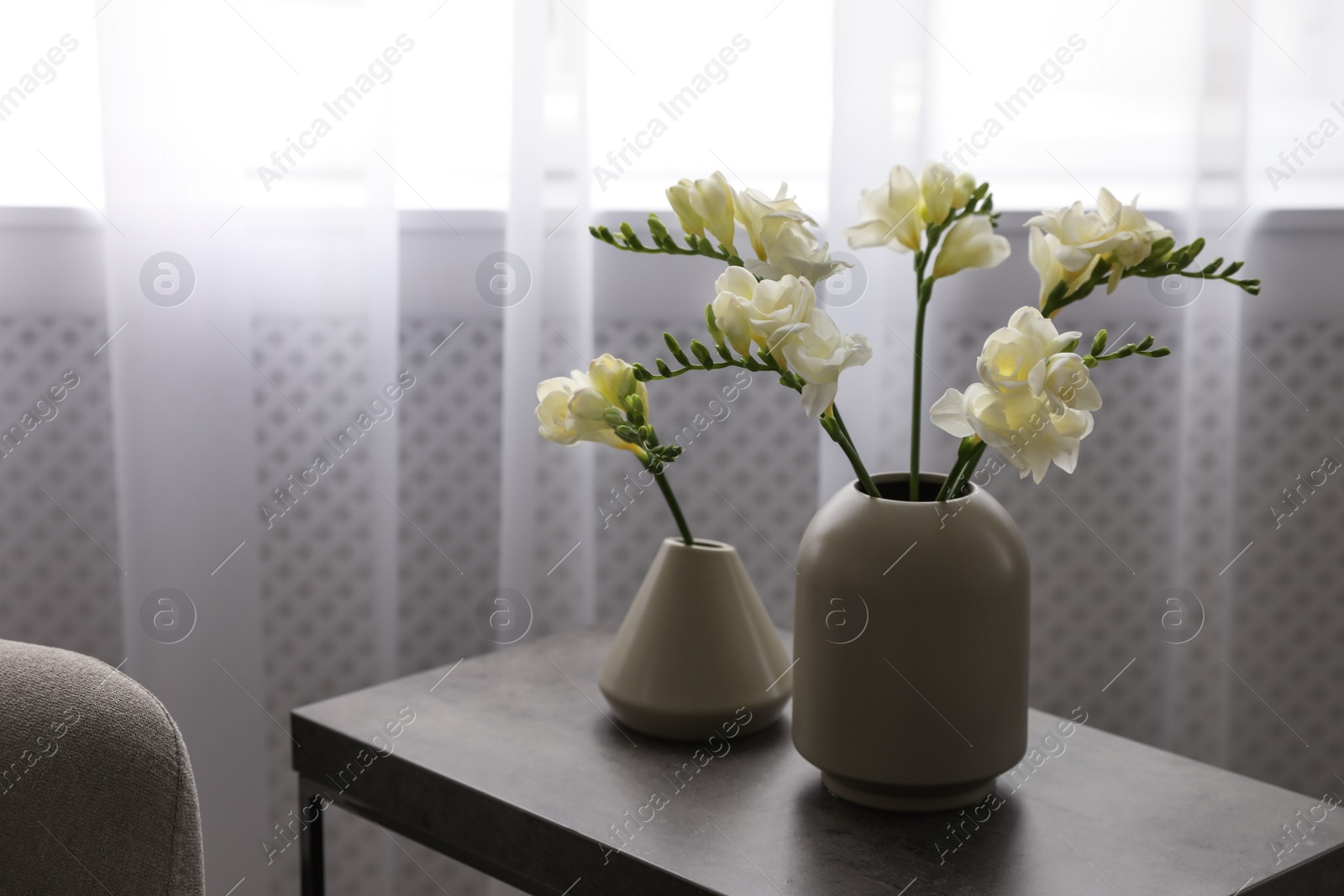 Photo of Beautiful spring freesia flowers on table in room