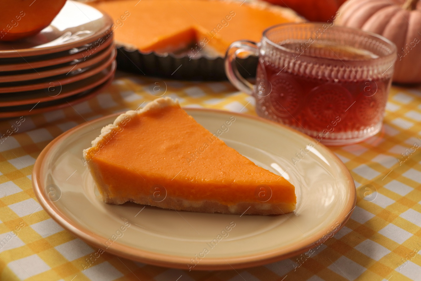 Photo of Piece of fresh homemade pumpkin pie served with tea on table