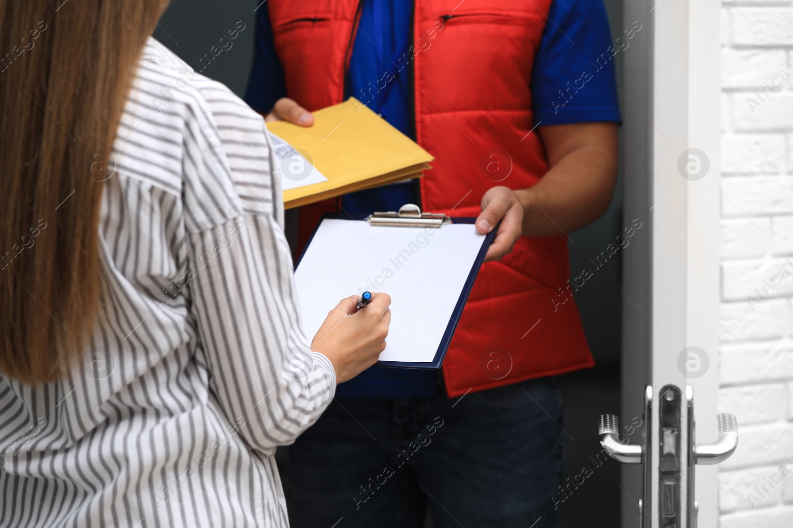 Photo of Woman signing for receiving padded envelopes on doorstep, closeup. Parcel delivery