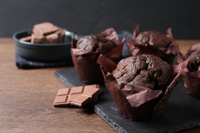 Photo of Tasty chocolate muffins on wooden table, closeup. Space for text