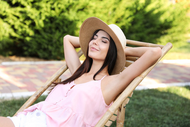 Image of Young woman resting in deck chair outdoors