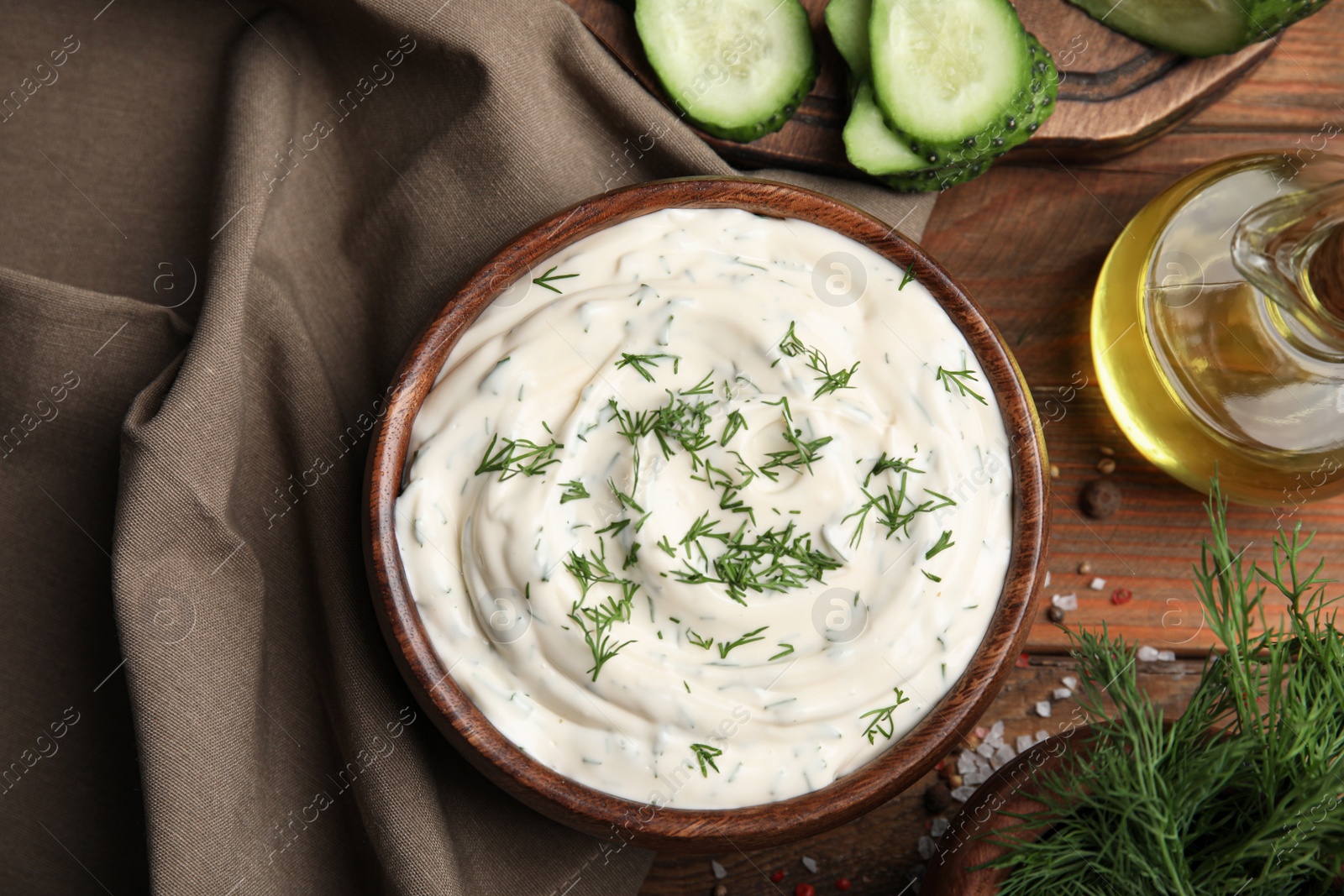 Photo of Tasty creamy dill sauce and ingredients on wooden table, flat lay