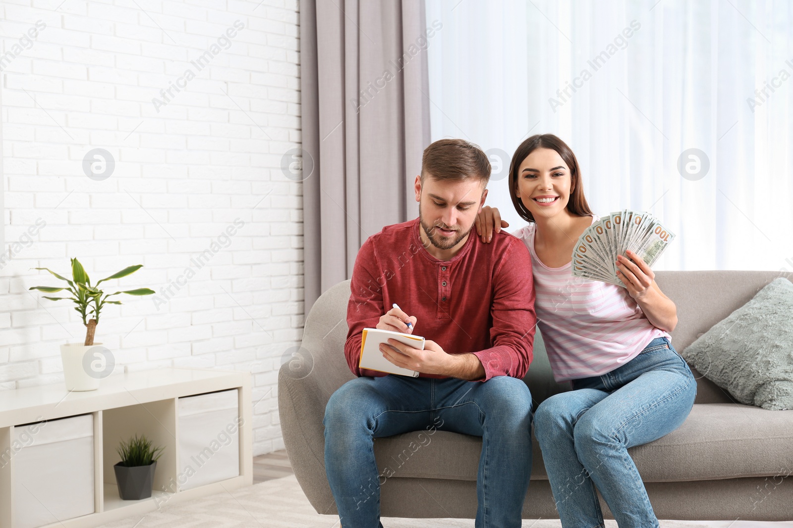 Photo of Beautiful young couple with money at home