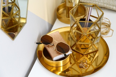 Photo of Gold tray with notebook, glasses and accessories on dressing table