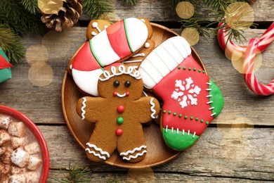 Different tasty Christmas cookies, cocoa with marshmallows and festive decor on wooden table, flat lay