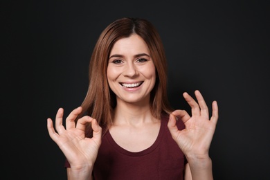 Photo of Woman showing OK gesture in sign language on black background