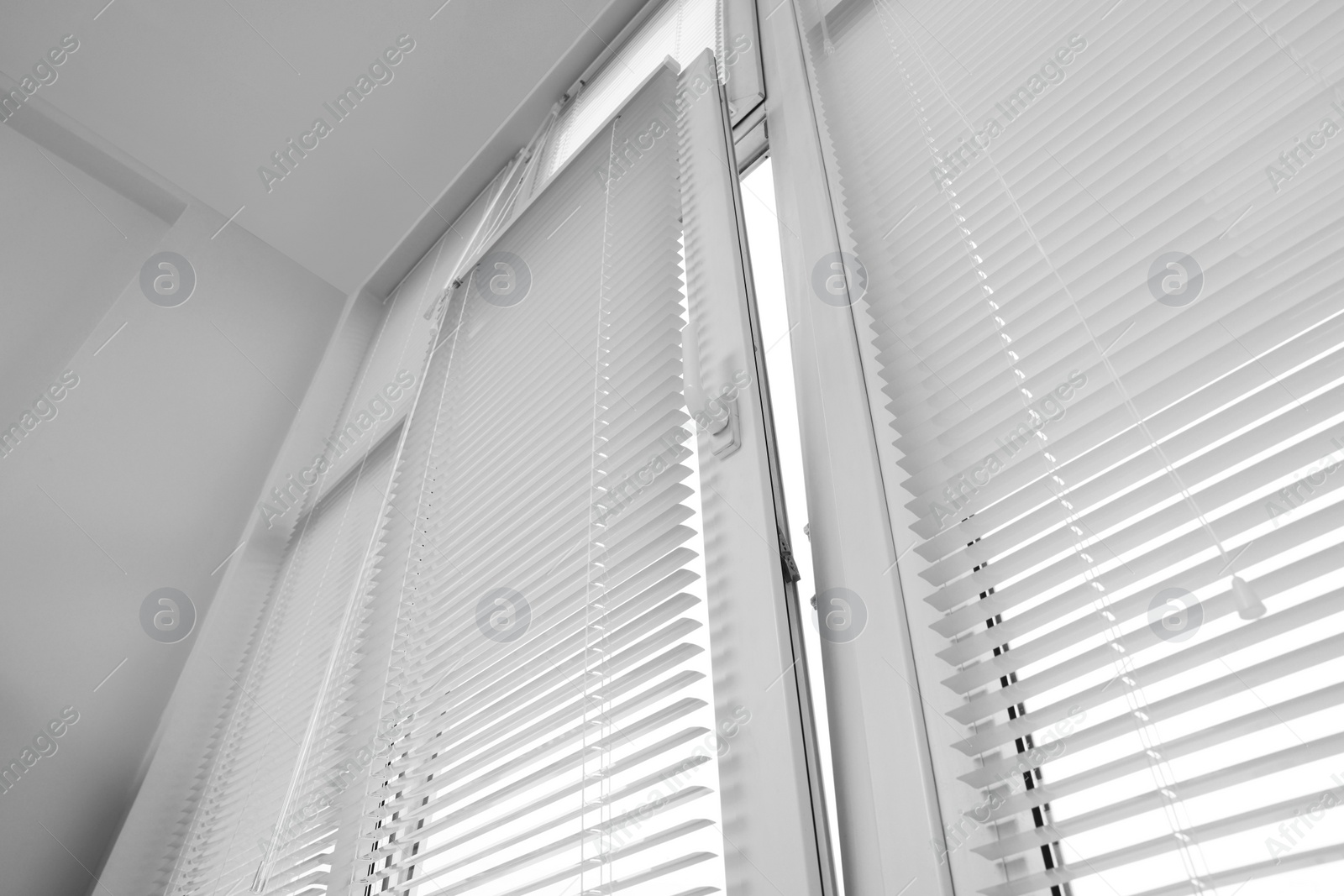 Photo of Stylish window with horizontal blinds in room, low angle view