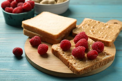 Photo of Delicious toasts with peanut butter and raspberries on light blue wooden table, closeup