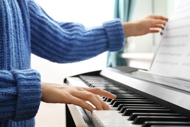 Photo of Young woman playing piano at home, closeup