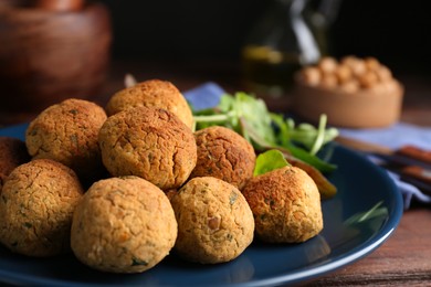 Delicious falafel balls with herbs on table, closeup