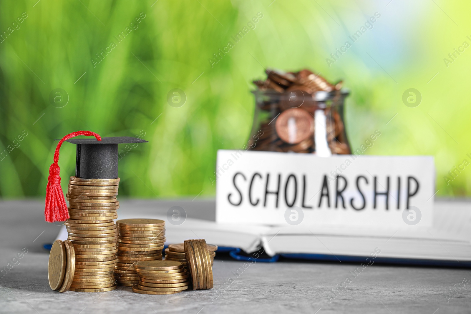 Photo of Scholarship concept. Coins and graduation cap on grey table, space for text