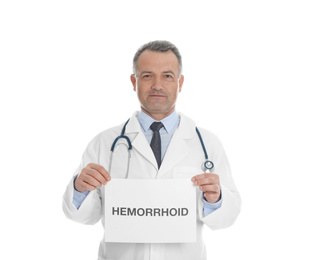 Photo of Doctor holding sign with word HEMORRHOID on white background