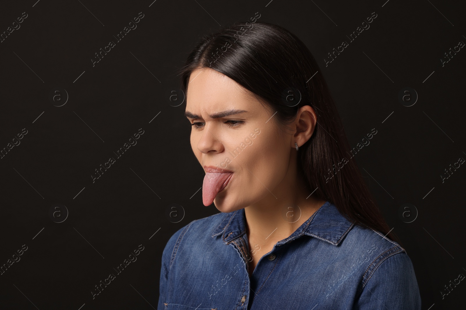 Photo of Personality concept. Emotional woman showing tongue on black background