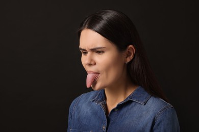 Photo of Personality concept. Emotional woman showing tongue on black background