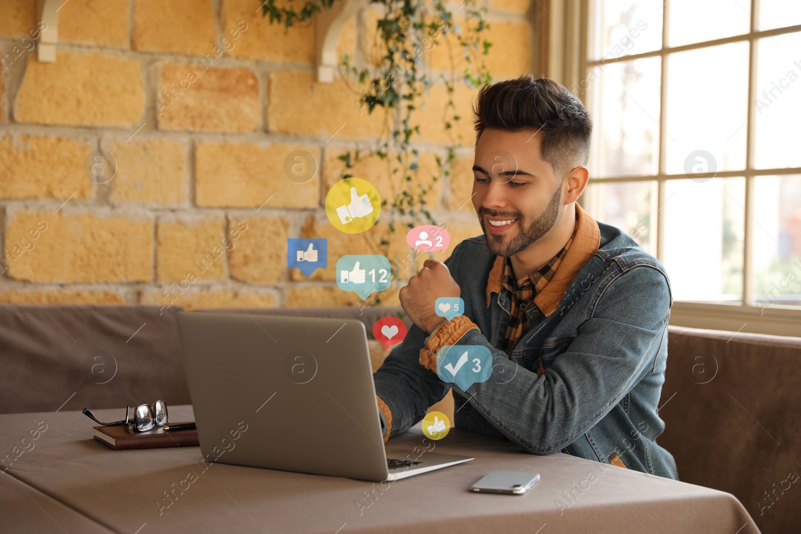 Image of Young blogger working with laptop at table in cafe