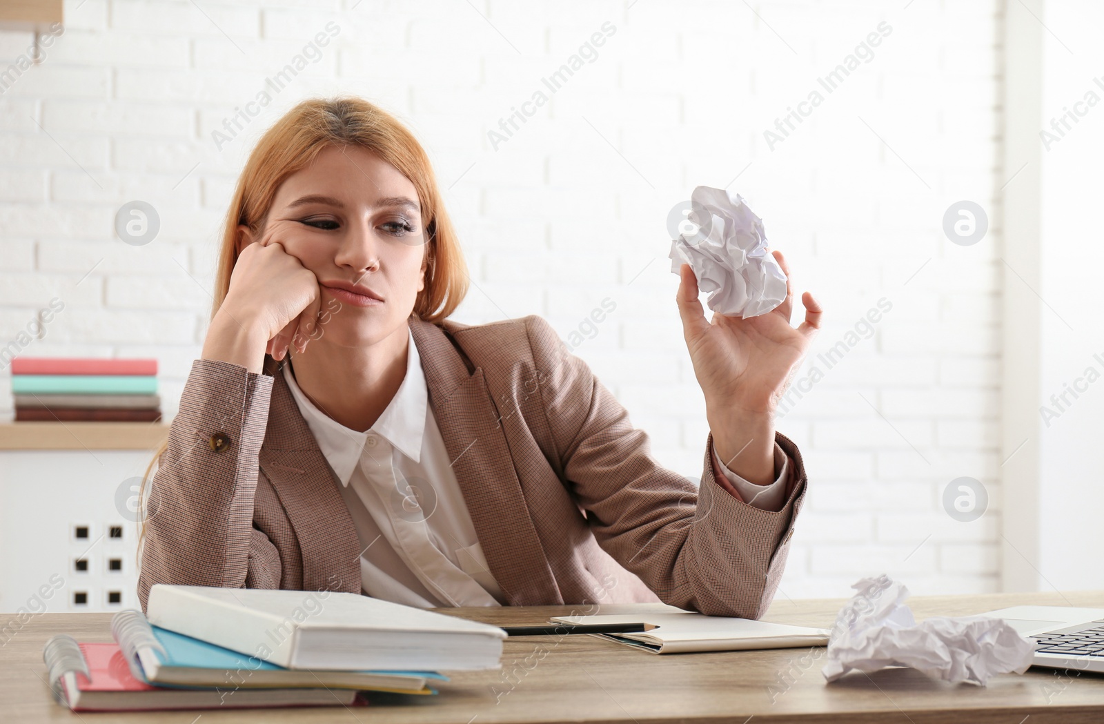 Photo of Lazy employee playing with crumpled paper at table in office