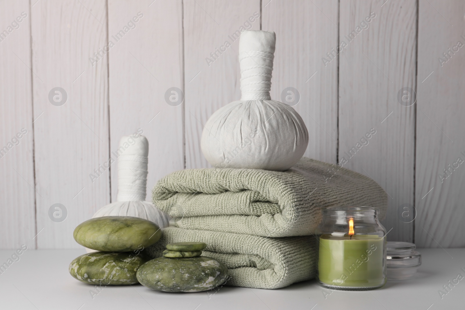 Photo of Composition with different spa products and candle on white table against wooden background