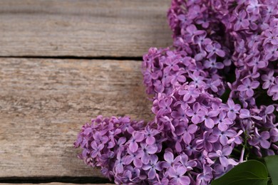 Photo of Beautiful lilac flowers on wooden table, closeup. Space for text