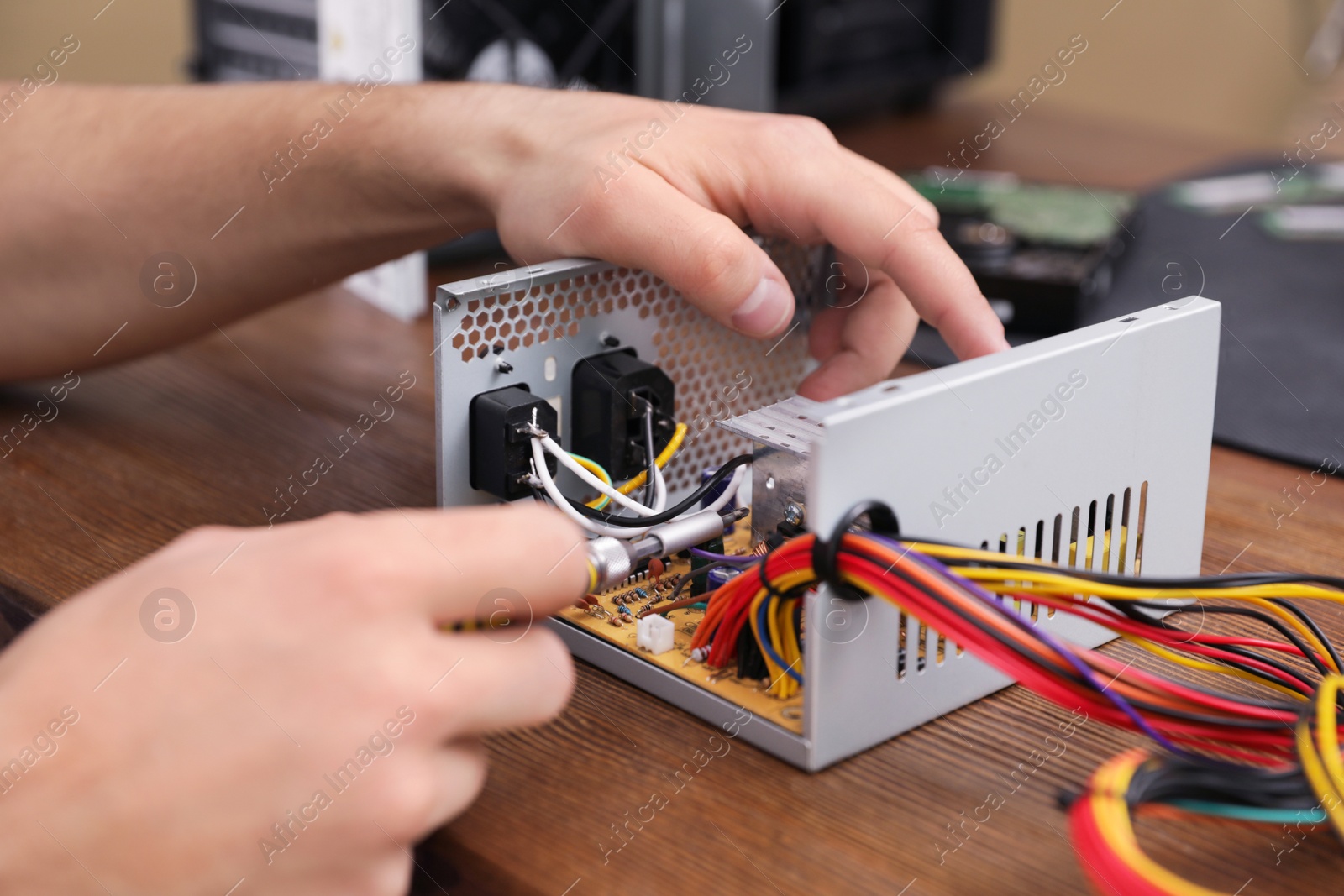 Photo of Male technician repairing power supply unit at table, closeup