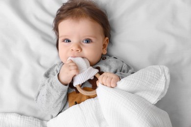 Cute little baby with toy on soft bed, top view